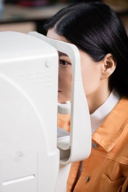 asian woman examining eyesight on blurred ophthalmoscope clipart
