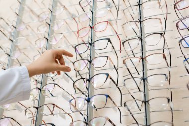 low angle view of cropped oculist taking eyeglasses in optics shop