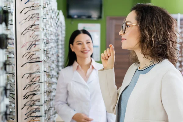 Young Woman Choosing Eyeglasses Asian Oculist Smiling Blurred Background —  Fotos de Stock
