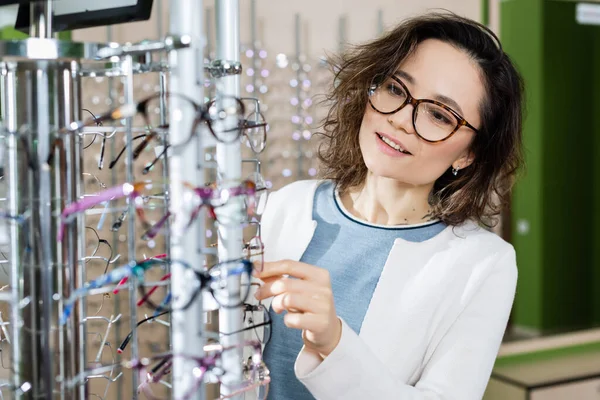 Young Positive Woman Choosing Eyeglasses Optics Salon Blurred Foreground — Foto Stock