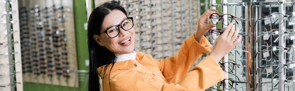 Mujer Asiática Emocionada Eligiendo Gafas Mirando Cámara Tienda Óptica Pancarta —  Fotos de Stock