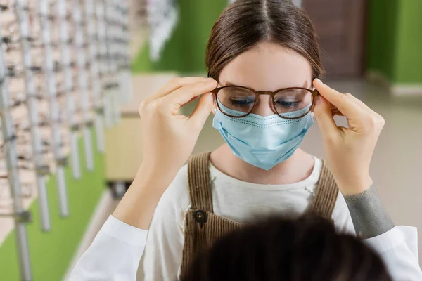 Blurred Ophthalmologist Trying Eyeglasses Girl Medical Mask Optics Salon — Stock Fotó