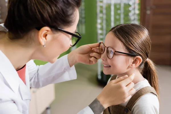 Oculist Putting Eyeglasses Cheerful Girl Optics Salon — Stockfoto