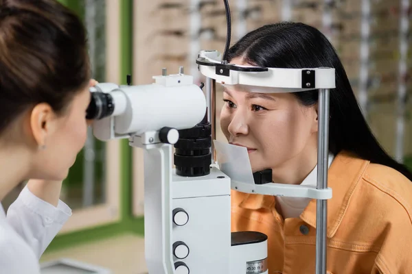 Blurred Optometrist Testing Eyesight Asian Woman Vision Screener Optics Shop — Stockfoto