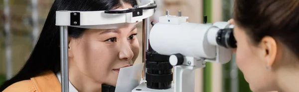 视力模糊的眼科医生在视觉检查仪 横幅上测量亚洲妇女的视力 — 图库照片