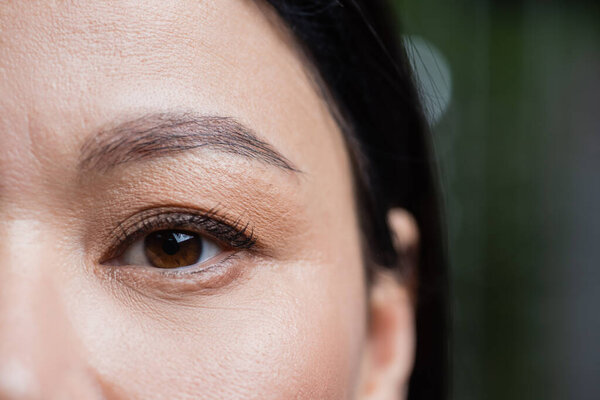 partial view of asian woman looking at camera, eye care concept