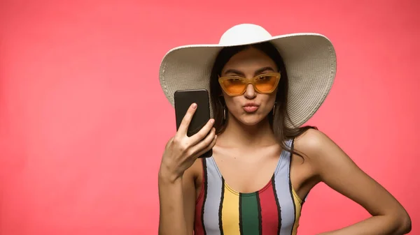 女性で太陽帽子と水着を保持携帯電話と置く唇絶縁オンピンク — ストック写真