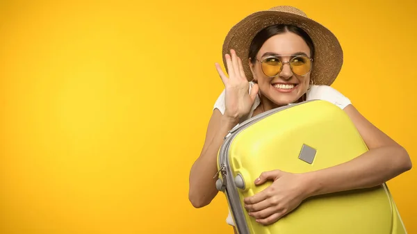 Smiling Tourist Sunglasses Holding Suitcase Waving Hand Isolated Yellow — Stockfoto