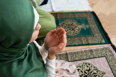 Overhead view of teen kid praying near mom at home  clipart