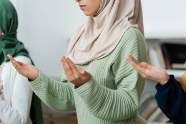 Cropped view of arabian woman praying near family at home  clipart