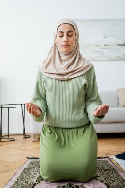 Geleneksel halı üzerinde dua eden tesettürlü Arap kadın. 