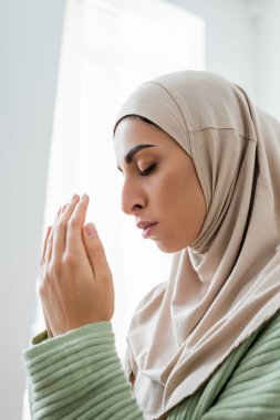 Müslüman kadın evde dua ederken gözlerini kapatıyor 