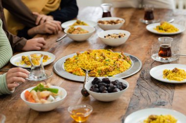 Masanın yanındaki müslüman aile manzarası pilav, hurma, baklava, çay ve bal ile servis ediliyor.