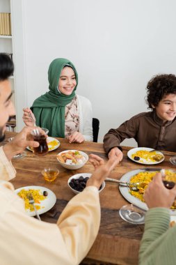 Mutlu ırklar arası Müslüman çocuklar evde bulanık ailelerle yemek yiyor.