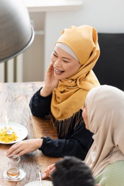 Yemekte Arap kızının yanında gülümseyen Asyalı Müslüman kadının yüksek açılı görüntüsü