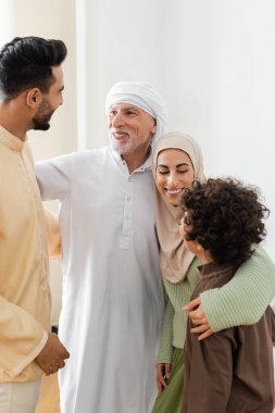 Evlerinde birbirlerine bakarken ırklar arası Müslüman aile kucaklaşması.