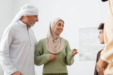 Mutlu Müslüman kadın olgun baba ve kocaya yakın Arap oğlunu işaret ediyor.
