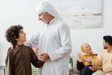 Arap torununun elini tutan olgun Müslüman adam evde ırklar arası bulanık bir ailenin yanında.