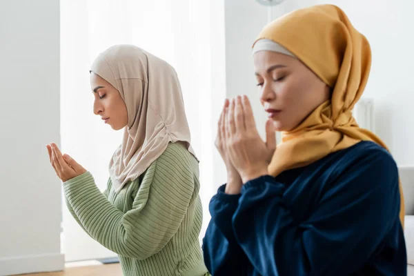 Joven Árabe Mujer Orando Cerca Borrosa Asiático Mamá Casa — Foto de Stock