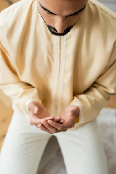 自宅でぼやけたカーペットの上で祈る若いアラビア人の男の高い角度ビュー — ストック写真