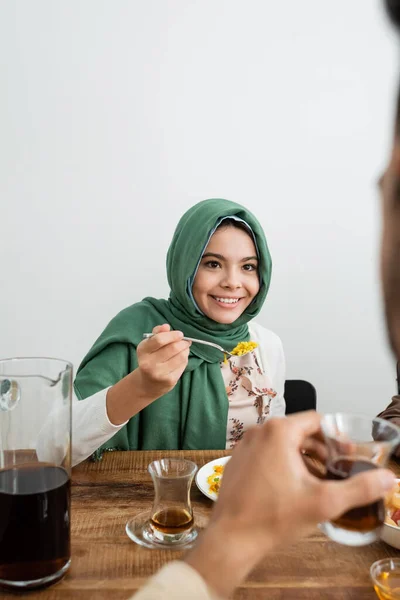 Šťastný Muslim Dívka Hidžábu Jíst Pilaf Blízkosti Rozmazaný Otec — Stock fotografie