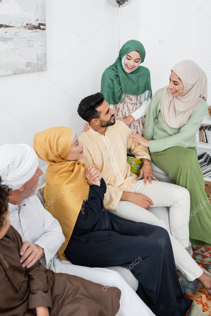 high angle view of arabian woman laughing near husband and multiethnic family at home