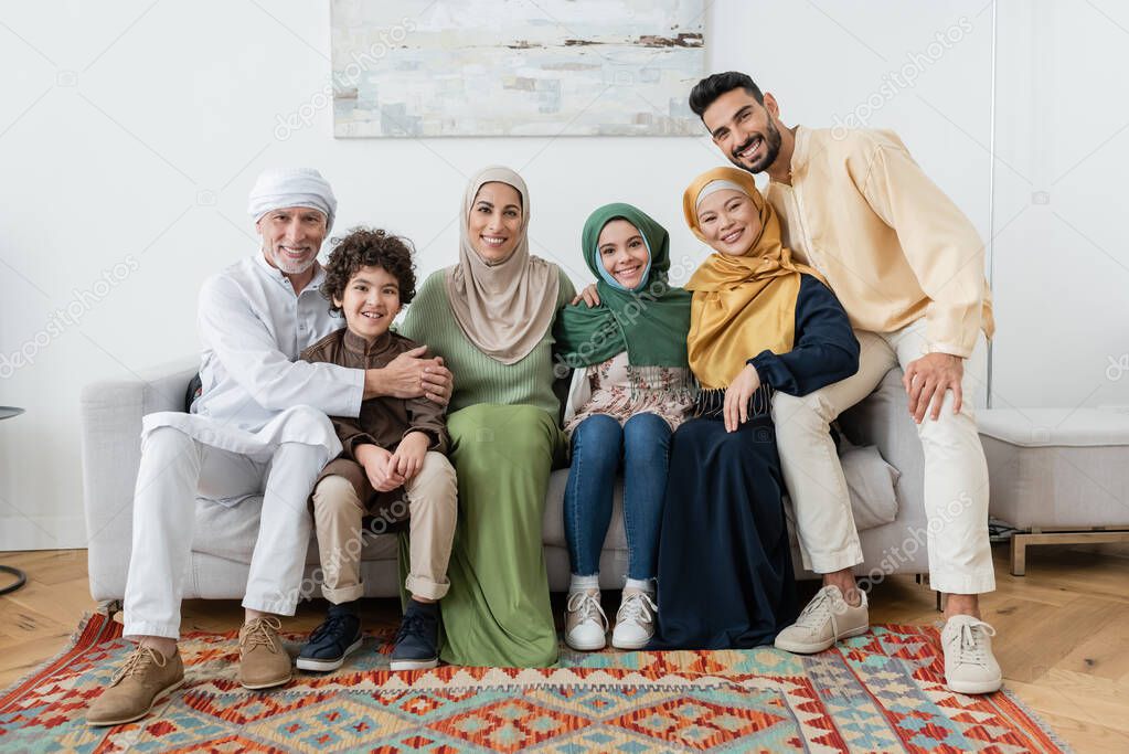 happy multiethnic muslim family looking at camera on sofa at home