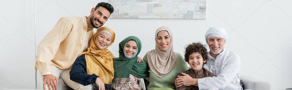 cheerful multicultural muslim family looking at camera at home, banner
