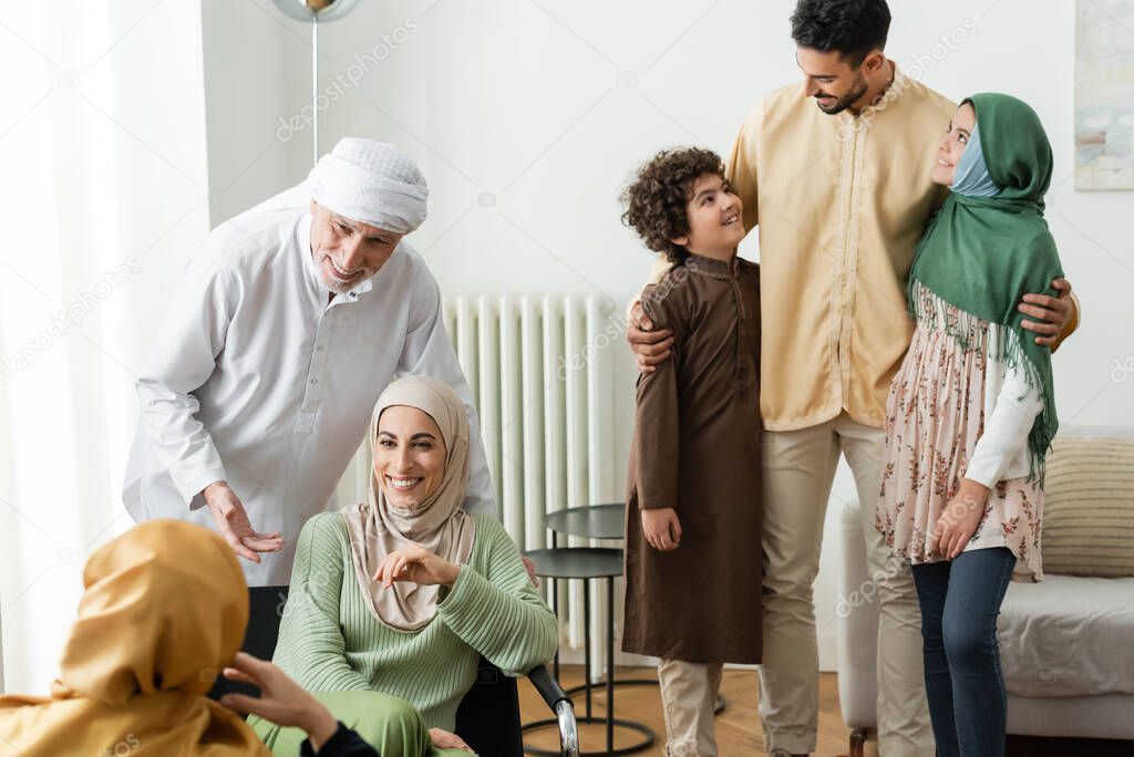 arabian man hugging interracial kids near muslim family at home