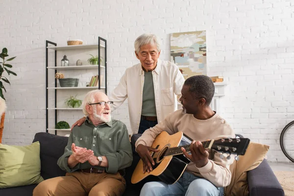 Positive Multiethnic Men Looking African American Friend Playing Acoustic Guitar — Stock Photo, Image