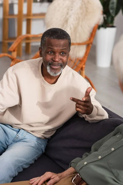 Sonriente Hombre Afroamericano Hablando Con Viejos Amigos Borrosos Sofá — Foto de Stock