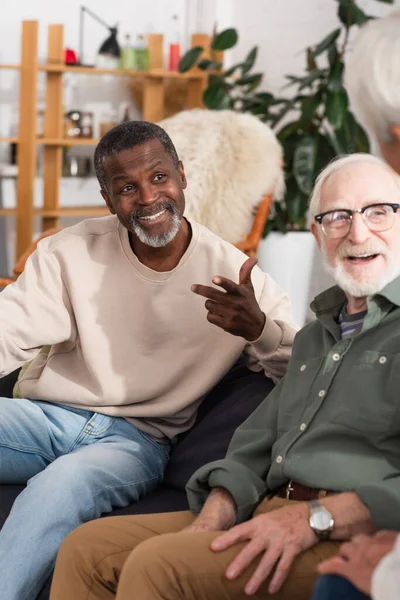 Fröhliche Multiethnische Männer Unterhalten Sich Mit Verschwommenem Freund Wohnzimmer — Stockfoto