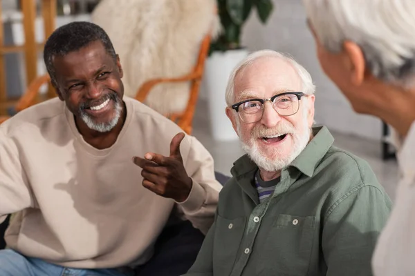 Ηλικιωμένος Άνδρας Που Γελάει Κοντά Πολυεθνικούς Φίλους Στο Σπίτι — Φωτογραφία Αρχείου