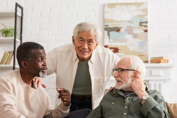 Smiling Asian Man Hugging Multiethnic Senior Friends Home — Stock Photo, Image