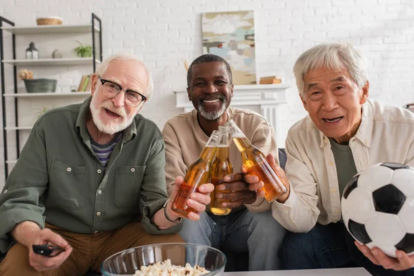 Positivo Interracial Senior Amigos Con Fútbol Cerveza Mirando Cámara Casa — Foto de Stock