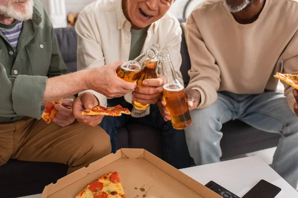 Обрезанный Вид Межрасовых Пенсионеров Звенящих Пивом Держащих Пиццу Дома — стоковое фото