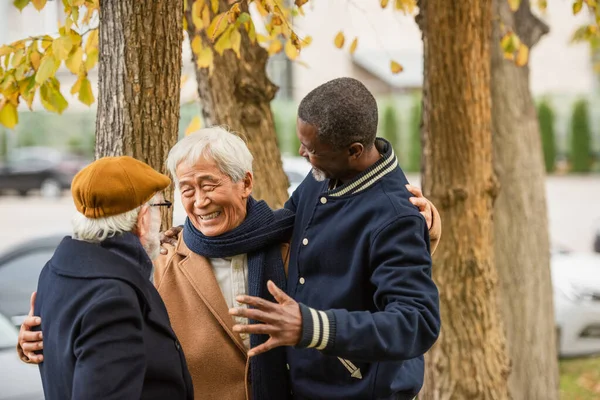 Ευτυχισμένος Ασιάτης Που Αγκαλιάζει Ηλικιωμένους Διαφυλετικούς Φίλους Στον Αστικό Δρόμο — Φωτογραφία Αρχείου