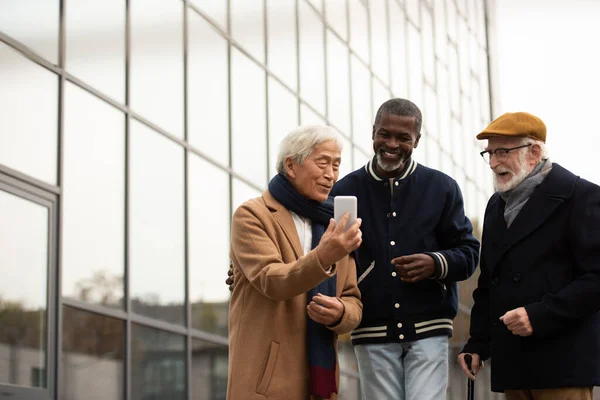 Hombre Asiático Senior Usando Smartphone Cerca Amigos Multiétnicos Calle Urbana —  Fotos de Stock