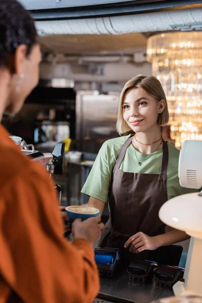 Sonriente Barista Sosteniendo Café Cerca Borrosa Cliente Afroamericano Cafetería — Foto de Stock