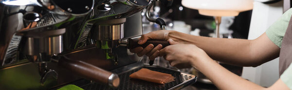Cropped view of barista working with coffee machine in cafeteria, banner 