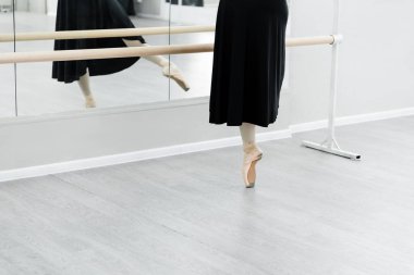 partial view of ballet dancer practicing at barre near mirrors clipart