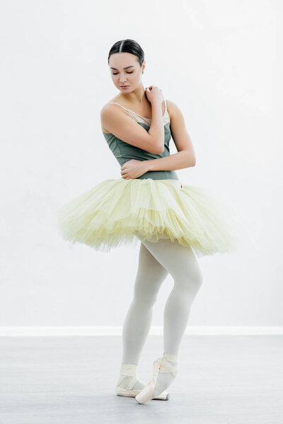 full length view of slim ballerina in tutu dancing in studio