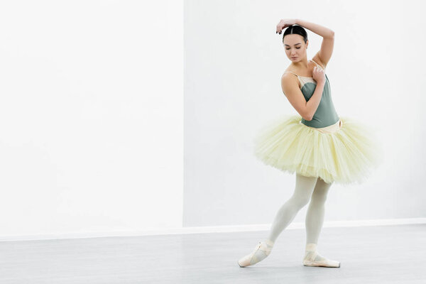full length view of graceful ballerina in tutu dancing in studio