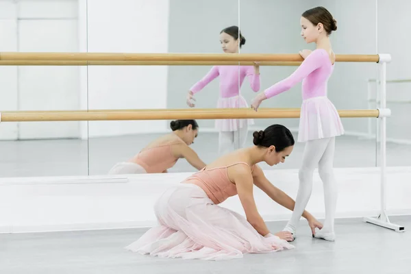 Nauczyciel Baletu Dotykając Stóp Dziewczyna Szkolenia Barre Pobliżu Luster — Zdjęcie stockowe