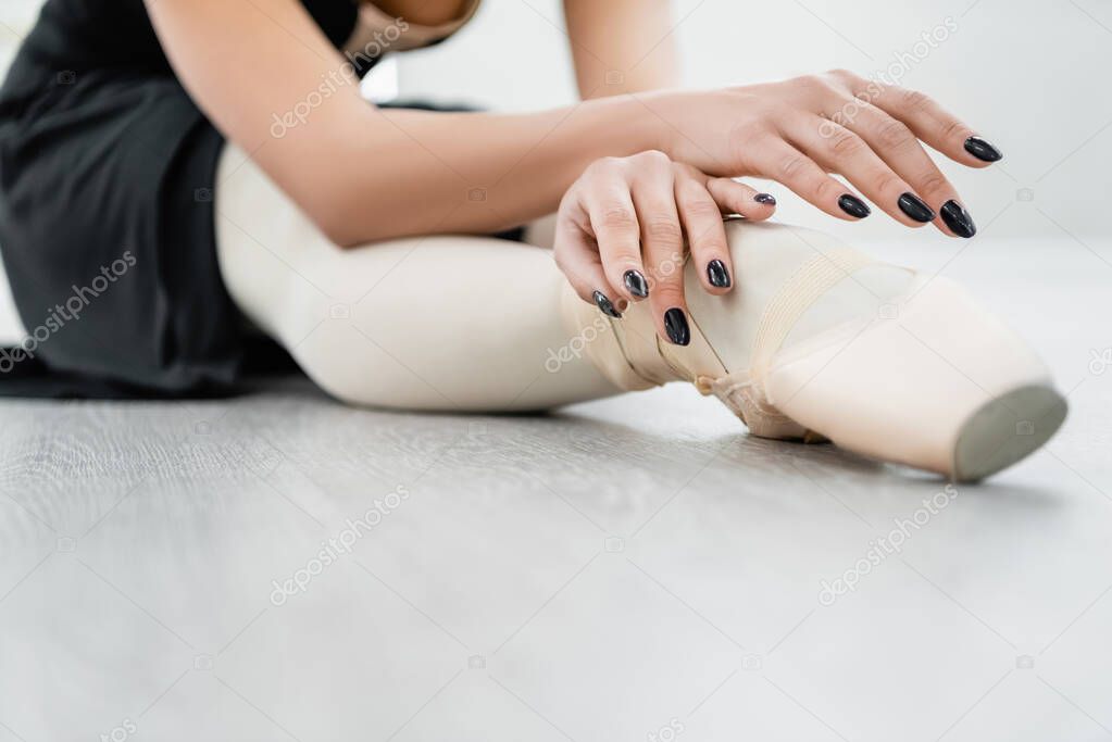cropped view of ballet dancer stretching on floor during rehearsal