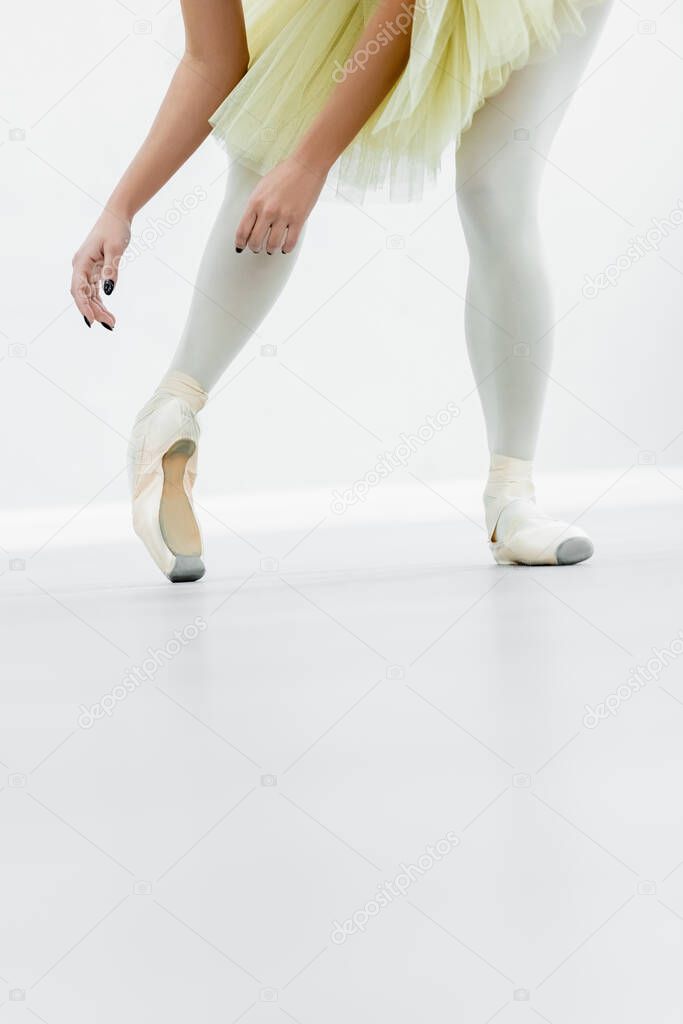 cropped view of ballerina in pointe shoes dancing during repetition