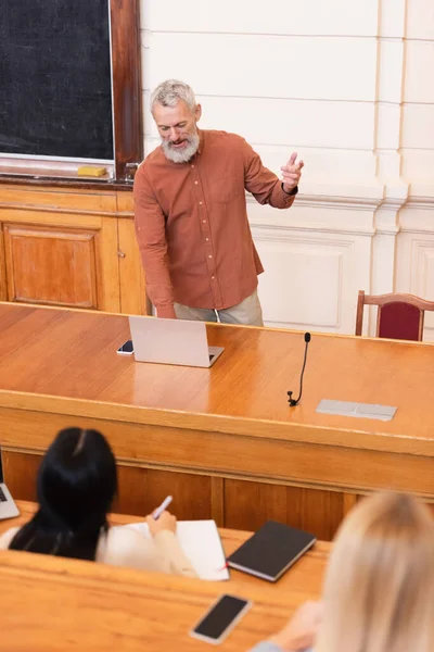 Teacher Using Laptop Blurred Students University — Stock Photo, Image