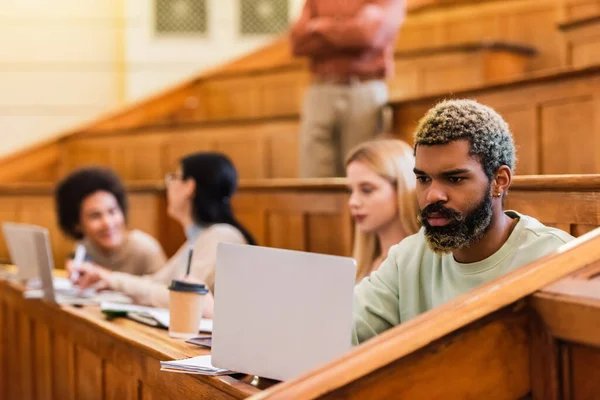 Afrykański Student Korzystający Laptopa Pobliżu Notebooka Rozmazanych Przyjaciół Uniwersytecie — Zdjęcie stockowe