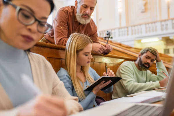 Estudiante Escribiendo Cuaderno Cerca Amigos Interracial Profesor Universidad —  Fotos de Stock