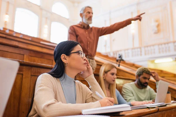 Estudiante Asiático Escribiendo Cuaderno Cerca Amigos Multiétnicos Profesor Auditorio Universitario — Foto de Stock